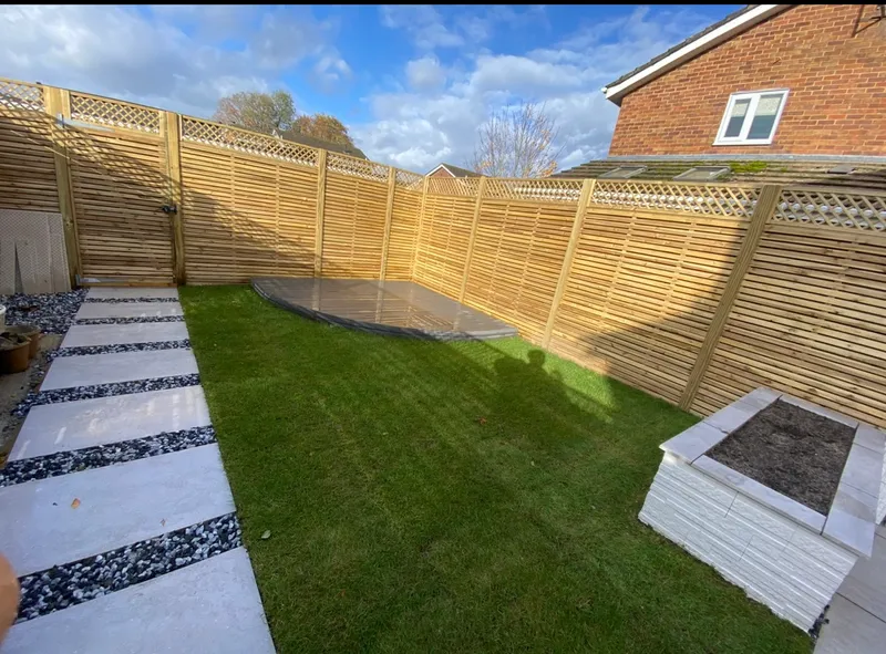 New horizontal slatted timber fence with a lattice trellis top and a matching gate, around a new lawn with a stepping-stone path